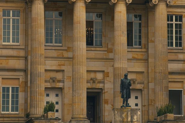 Fachada clássica de um edifício institucional com colunas e uma estátua na entrada.