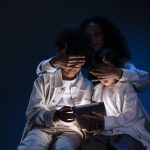 Mãe acompanha duas crianças enquanto elas usam um tablet.
